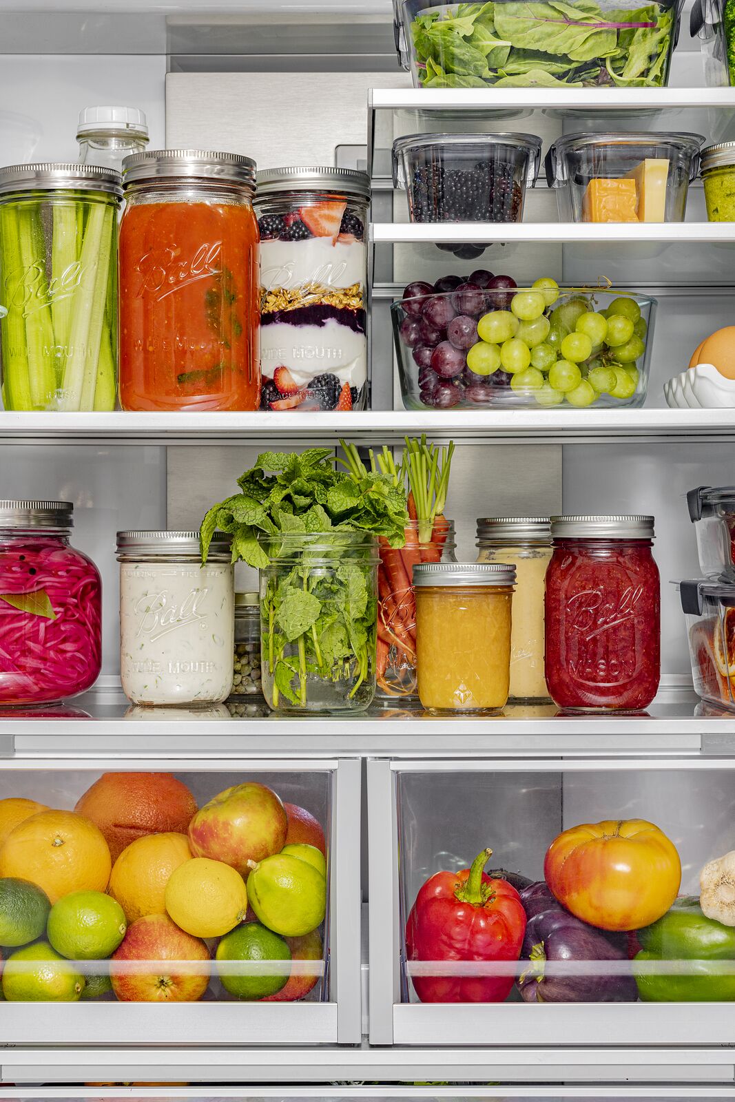 Refrigerator shelves of Ball jars holding preserves, pickles and cut vegetables