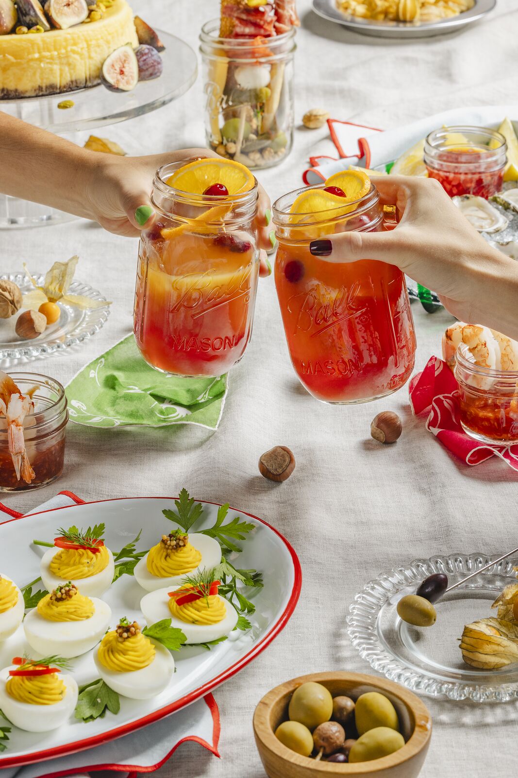 Hand lifting a Ball jar drink from a crowded party table