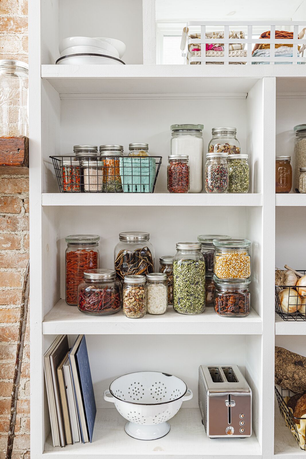 Open pantry shelves lined with Ball jars of grains, spices and preserves