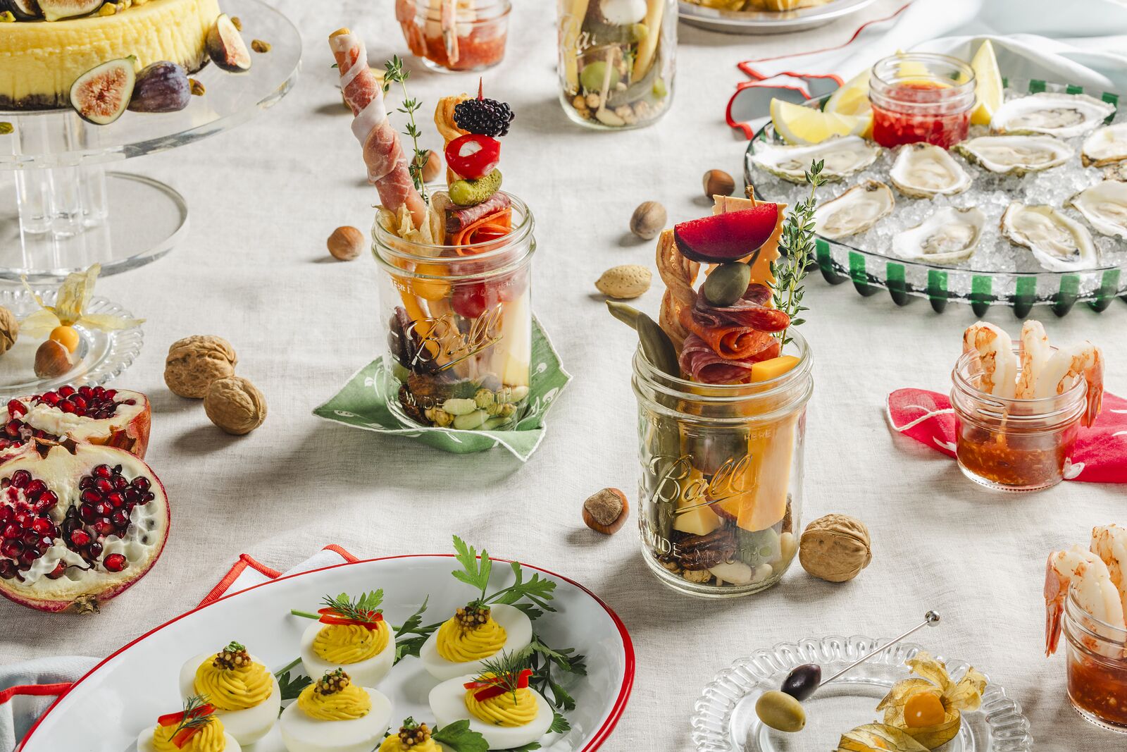 Party spread using Ball jars as individual snack cups beside deviled eggs and oysters