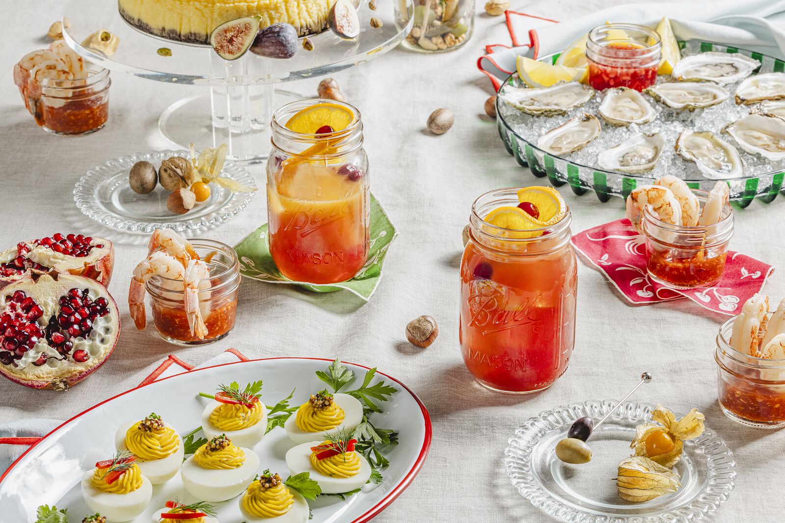 Wide party table of jar drinks, deviled eggs, pomegranate and sweets